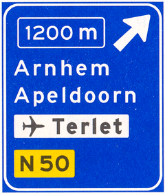 Verkeersbord K2: Voorwegwijzer langs autosnelweg voor de afgaande richting, met afstandaanduiding, afritnummer, interlokale doelen (bovenste doel = afritnaam), verwijzing naar vliegveld/luchthaven en routenummer niet-
